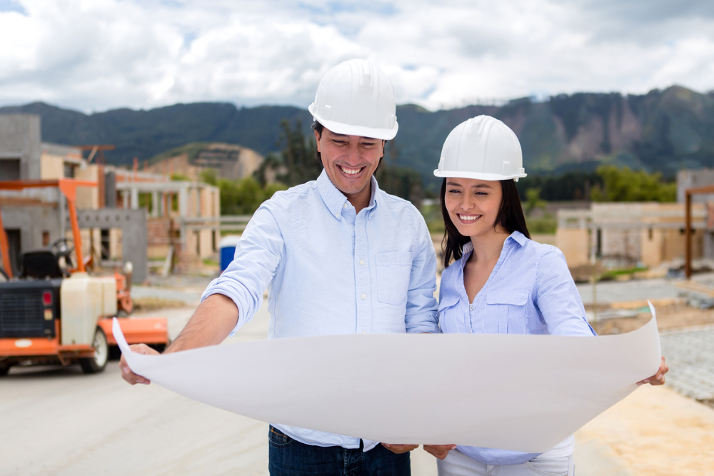 Happy couple with blueprints of their new house